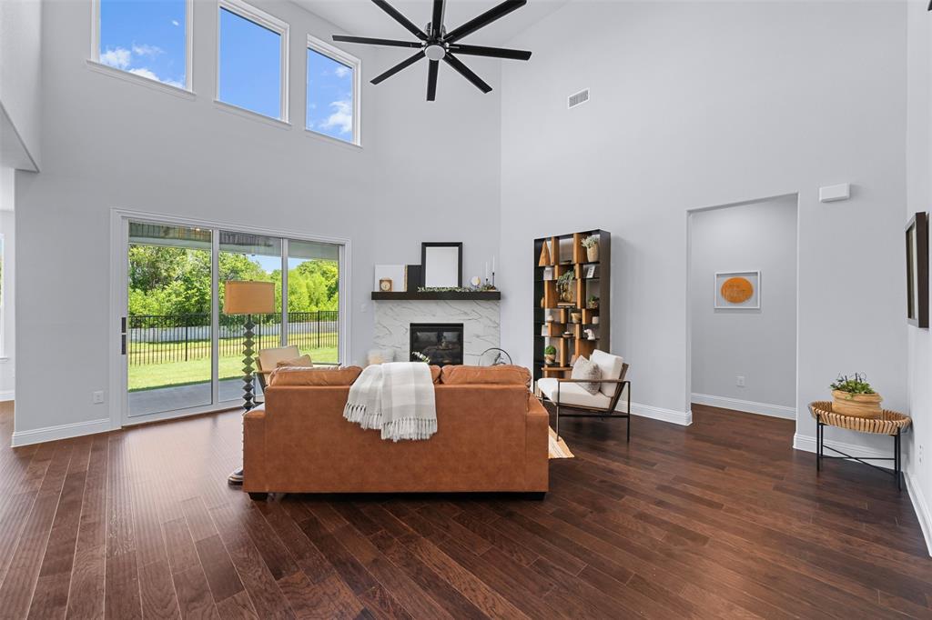 1173 Rochester Place Copper Canyon, TX 75077 - Photo 13 of 34 This living room features dark hardwood flooring, a fireplace with a light-colored surround, and a ceiling fan