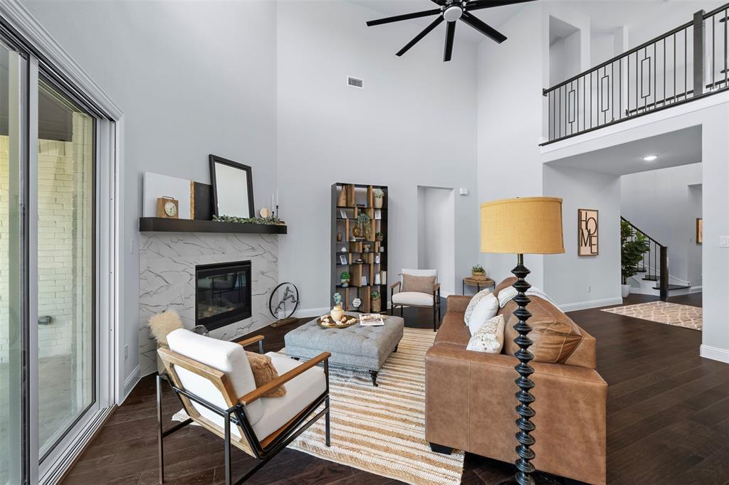1173 Rochester Place Copper Canyon, TX 75077 - Photo 14 of 34 Living room featuring high ceilings, dark hardwood floors, a modern fireplace with a light-colored marble surround, and sliding glass doors