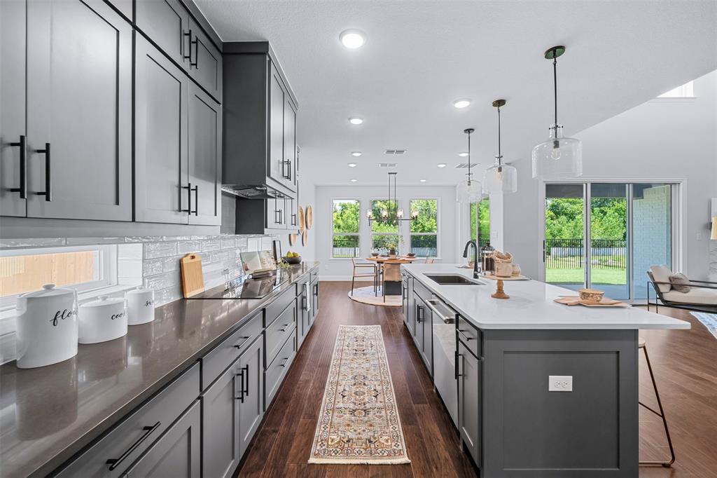 1173 Rochester Place Copper Canyon, TX 75077 - Photo 20 of 34 The kitchen features dark wood floors, shaker-style cabinetry with matte black hardware, and a center island with a sink and pendant lighting