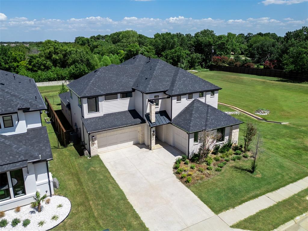 1173 Rochester Place Copper Canyon, TX 75077 - Photo 31 of 34 The property features an extensive lawn with mature trees, a driveway, and a well-maintained exterior with a dark roof and light-colored siding