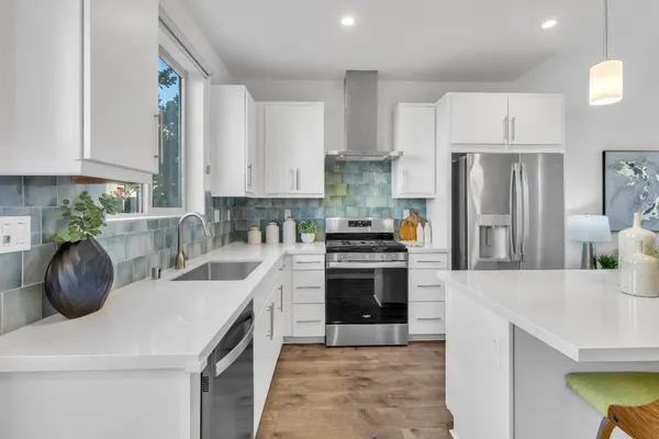 a kitchen with stainless steel appliances granite countertop a sink a stove a refrigerator and a white cabinets