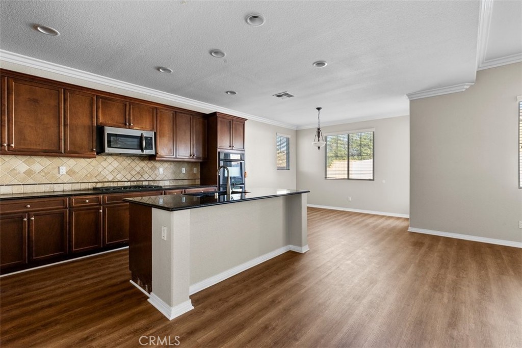 820 Volande Court Perris, CA 92571 - Photo 10 of 37 a kitchen with granite countertop wooden floors and white stainless steel appliances