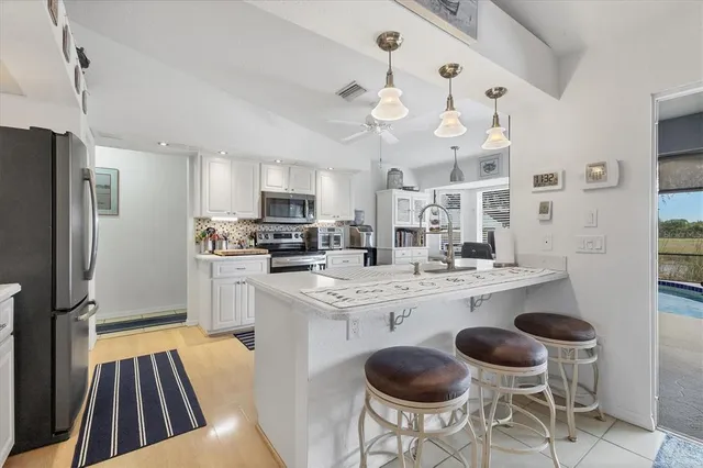 a kitchen with stainless steel appliances a dining table chairs sink and stove top oven