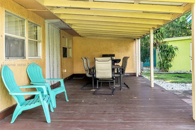 a view of a patio with table and chairs with wooden floor and fence
