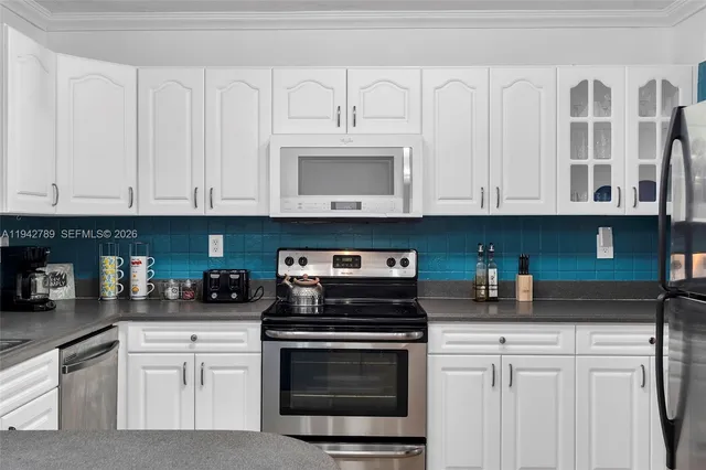 a kitchen with stainless steel appliances granite countertop grey cabinets a stove a sink and dishwasher