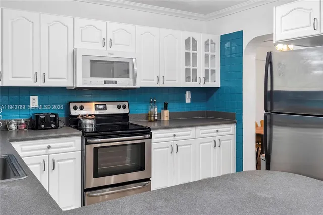 a kitchen with stainless steel appliances granite countertop a refrigerator stove and white cabinets