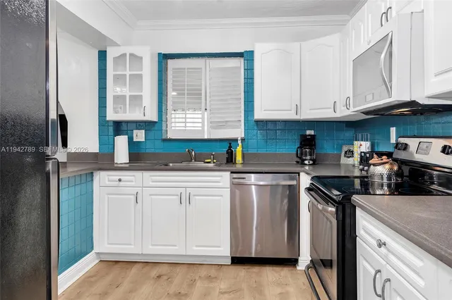 a kitchen with stainless steel appliances granite countertop a sink a stove a refrigerator and cabinets