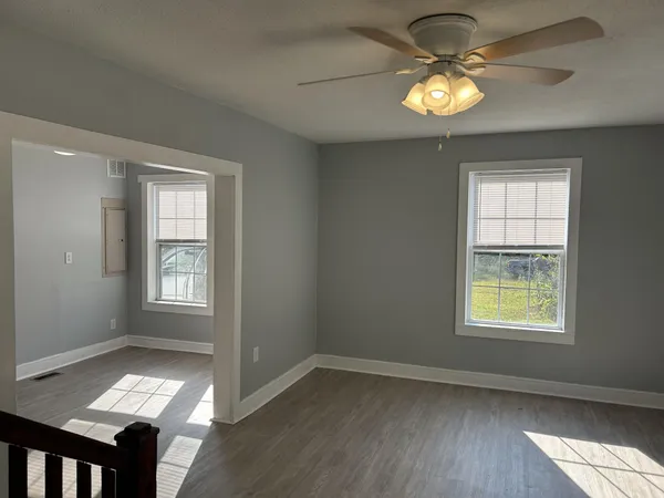 a view of an empty room with a window and wooden floor