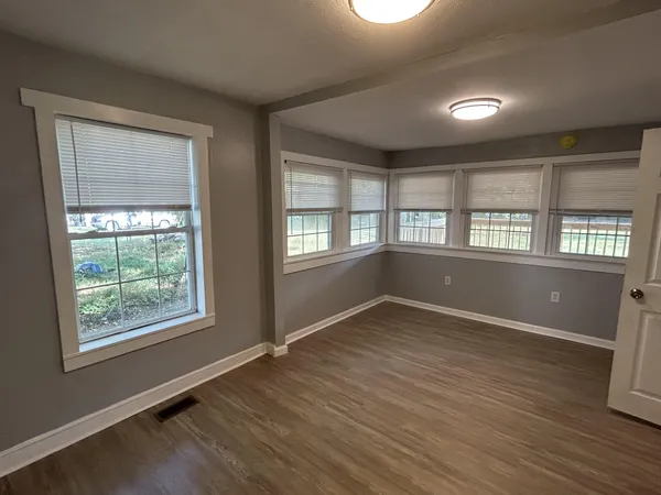 an empty room with wooden floor and windows