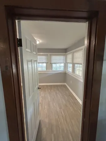 a view of an empty room with wooden floor and a window
