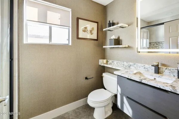 a bathroom with a granite countertop toilet sink and mirror
