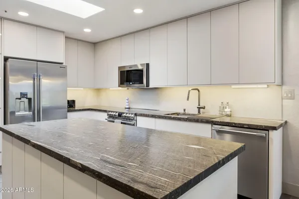 a kitchen with granite countertop a sink a counter top space appliances and cabinets