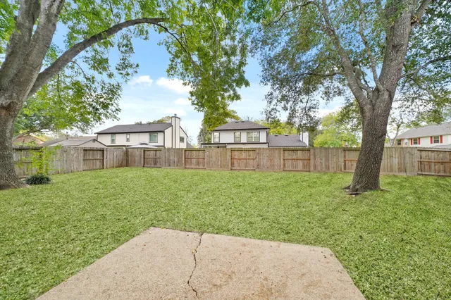 a view of a yard in front of a house with large trees