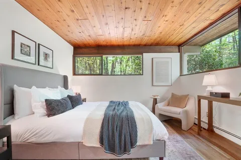 a bedroom with a bed a mirror and a large window