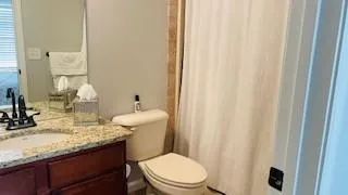 a bathroom with a granite countertop sink toilet and a mirror