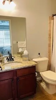 a bathroom with a granite countertop sink toilet and mirror