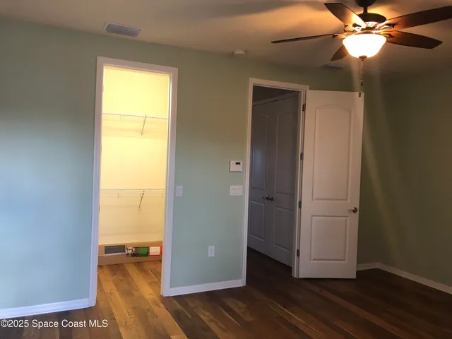a view of empty room with wooden floor and fan