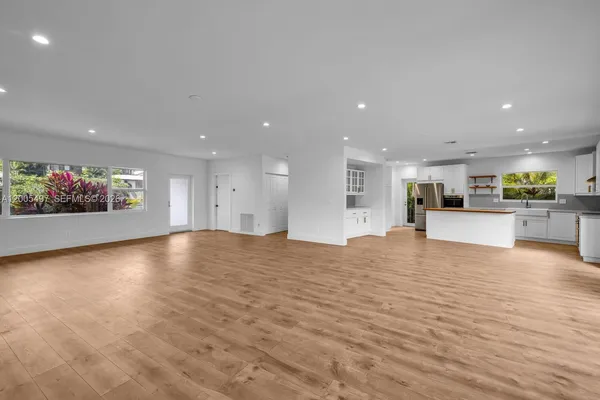 a view of kitchen and a hall with wooden floor