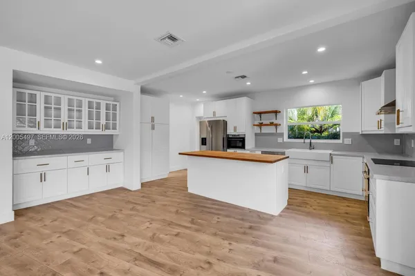 a large kitchen with stainless steel appliances kitchen island a large counter top and a stove top oven
