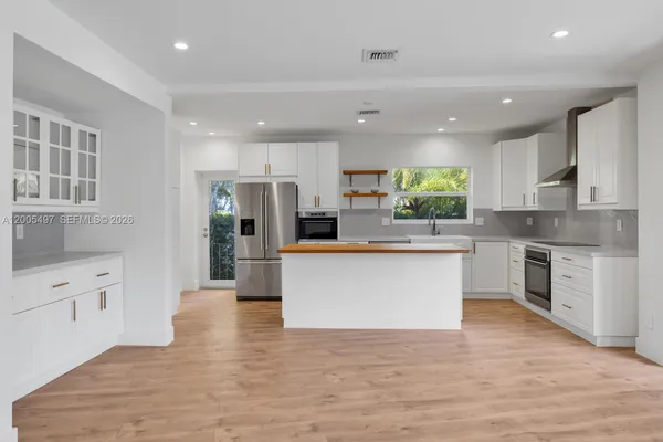 a large kitchen with stainless steel appliances kitchen island a large counter top and a wooden floors