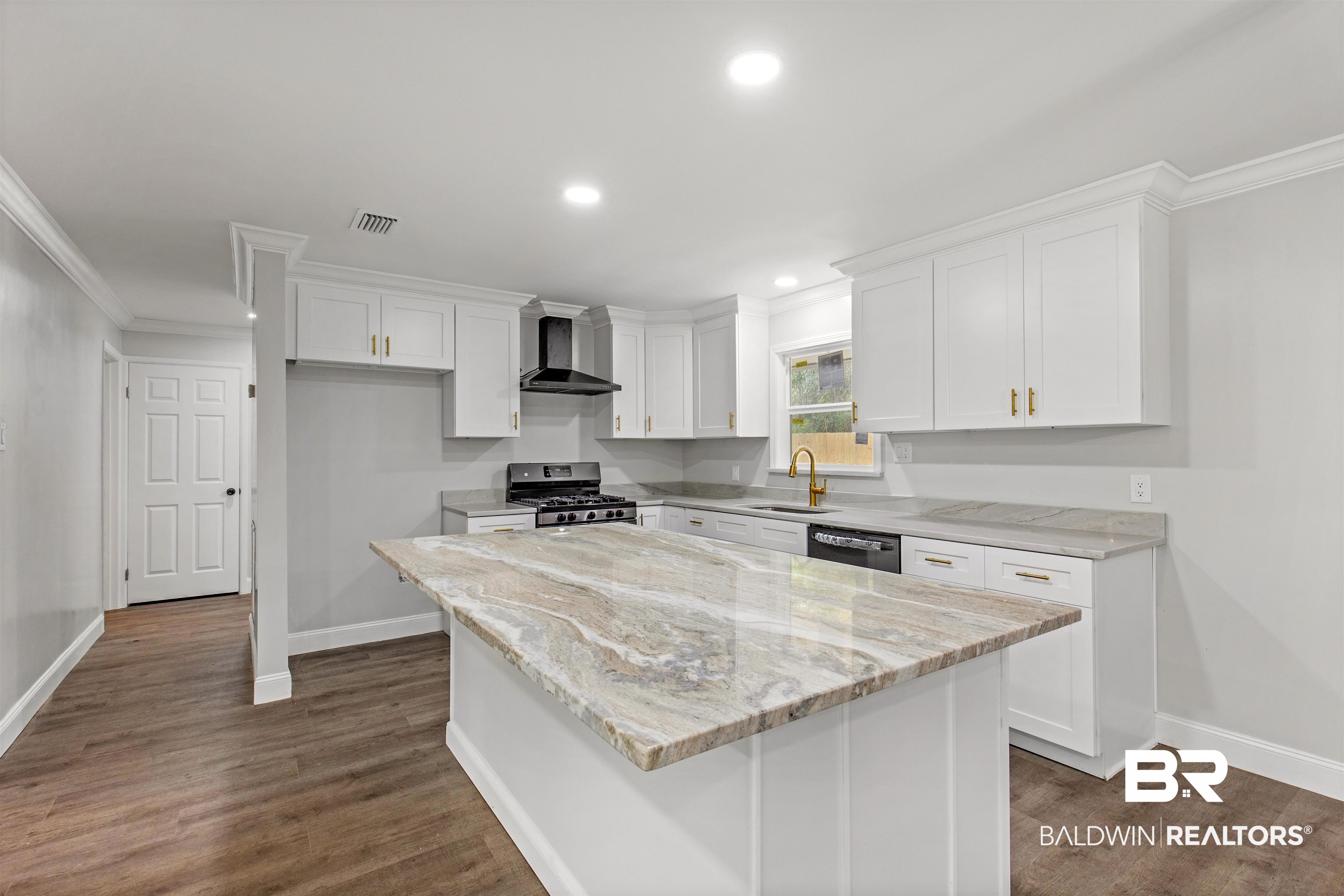 1432 South Polaris Drive Mobile, AL 36693 - Photo 6 of 27 Kitchen featuring ornamental molding, white cabinetry, appliances with stainless steel finishes, a center island, and wall chimney range hood