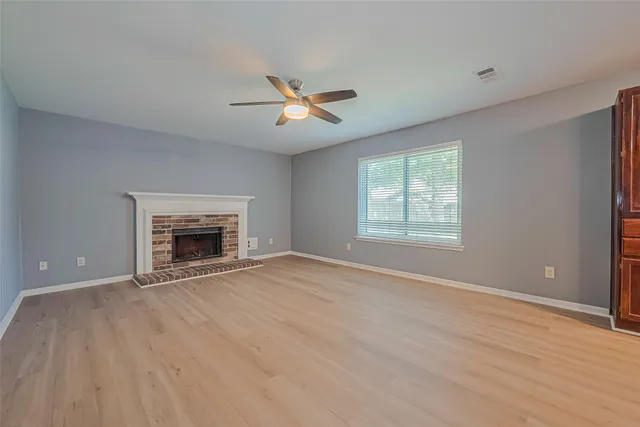 a view of empty room with fireplace and wooden floor