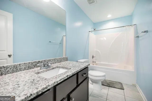 a bathroom with a granite countertop sink a toilet and shower