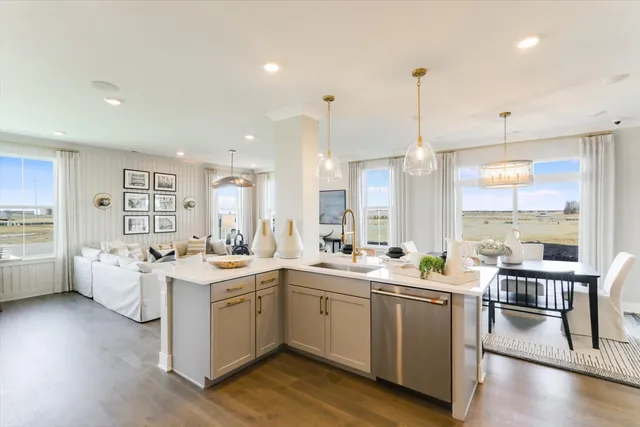 a large white kitchen with a stove a sink dishwasher and a dining table with wooden floor