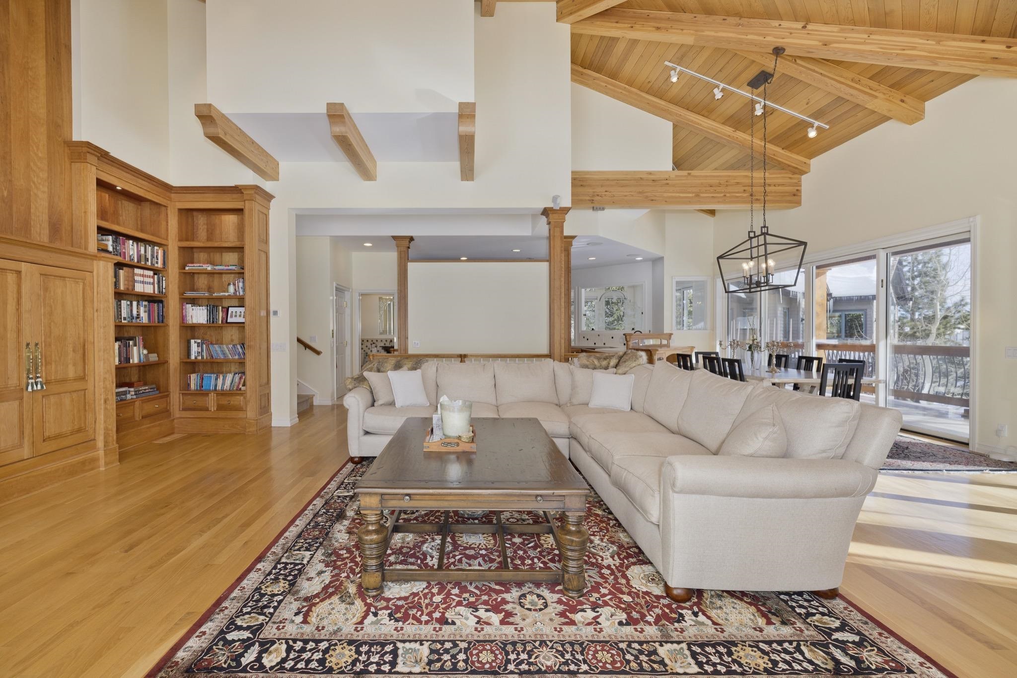 Living room with high vaulted ceiling, a wood ceiling with exposed beams, ornate columns, and light wood-style floors