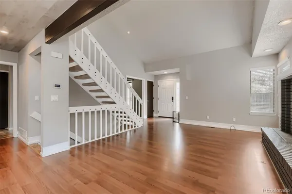 a view of an empty room with wooden floor and stairs