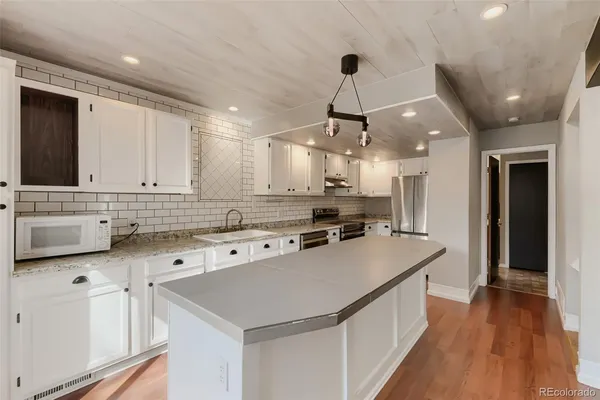 a kitchen with kitchen island a sink appliances and cabinets