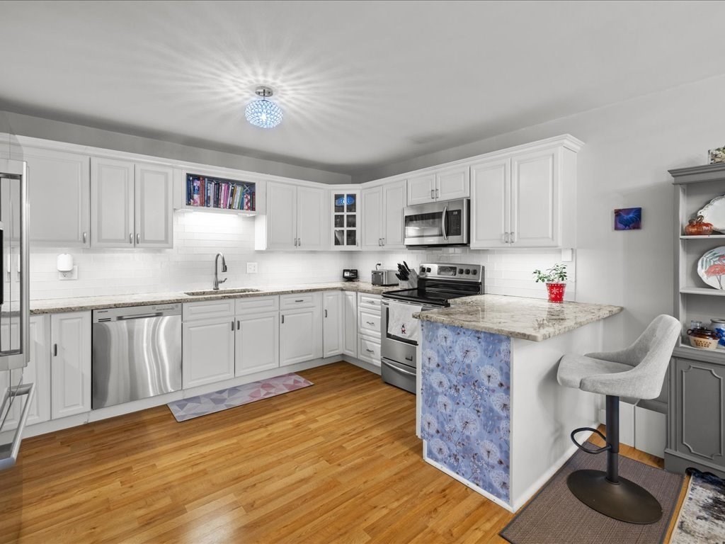 4 Strathmore Shire Drive, Unit B Uxbridge, MA 01569 - Photo 16 of 41 a kitchen with granite countertop a stove top oven a sink a counter space and cabinets