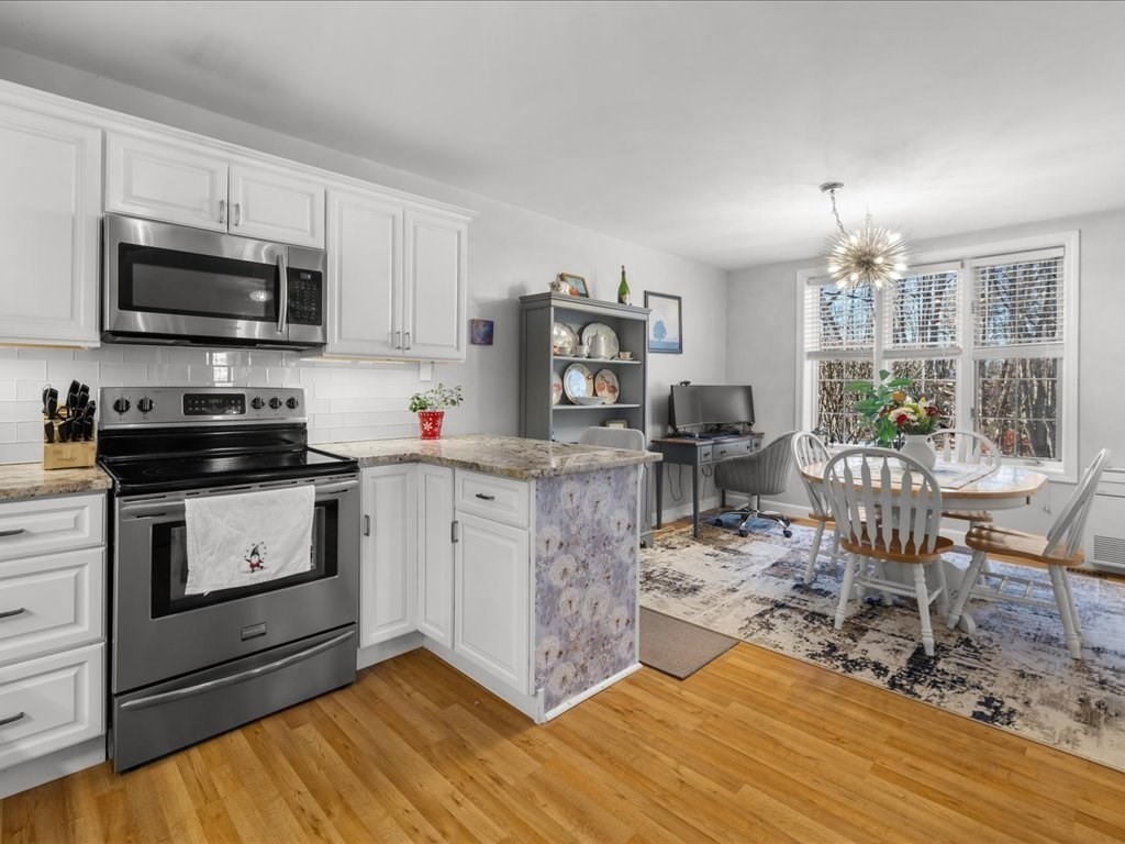 4 Strathmore Shire Drive, Unit B Uxbridge, MA 01569 - Photo 19 of 41 a kitchen with stainless steel appliances granite countertop a stove top oven a sink dishwasher a dining table and chairs with wooden floor