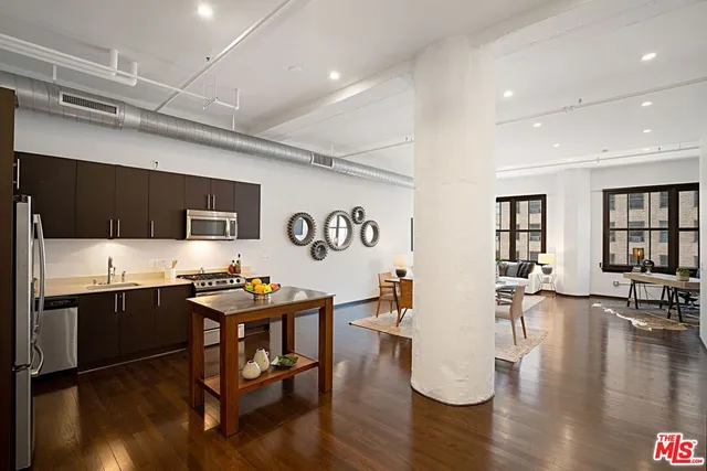 a room with stainless steel appliances kitchen island granite countertop a dining table chairs stove and white cabinets