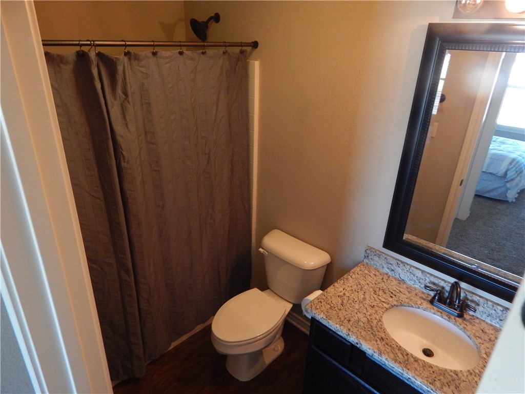 3500 South College Avenue, Unit 204 Bryan, TX 77801 - Photo 4 of 7 a bathroom with a sink a toilet a mirror and shower curtain