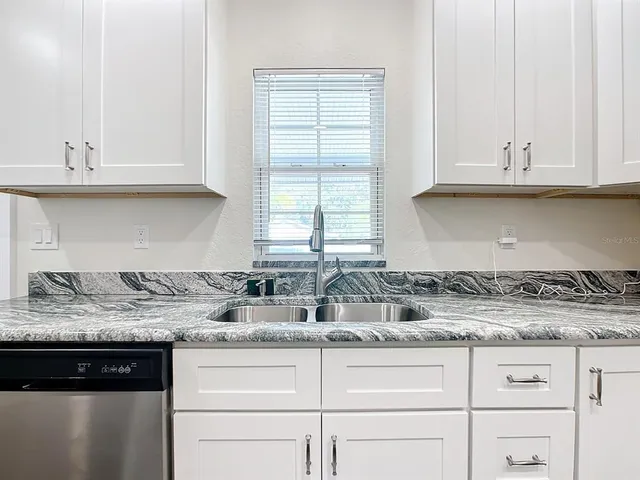 a kitchen with granite countertop white cabinets and a sink