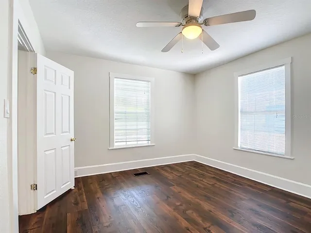 a view of an empty room with window and wooden floor