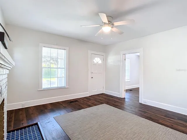 an empty room with wooden floor fan and windows