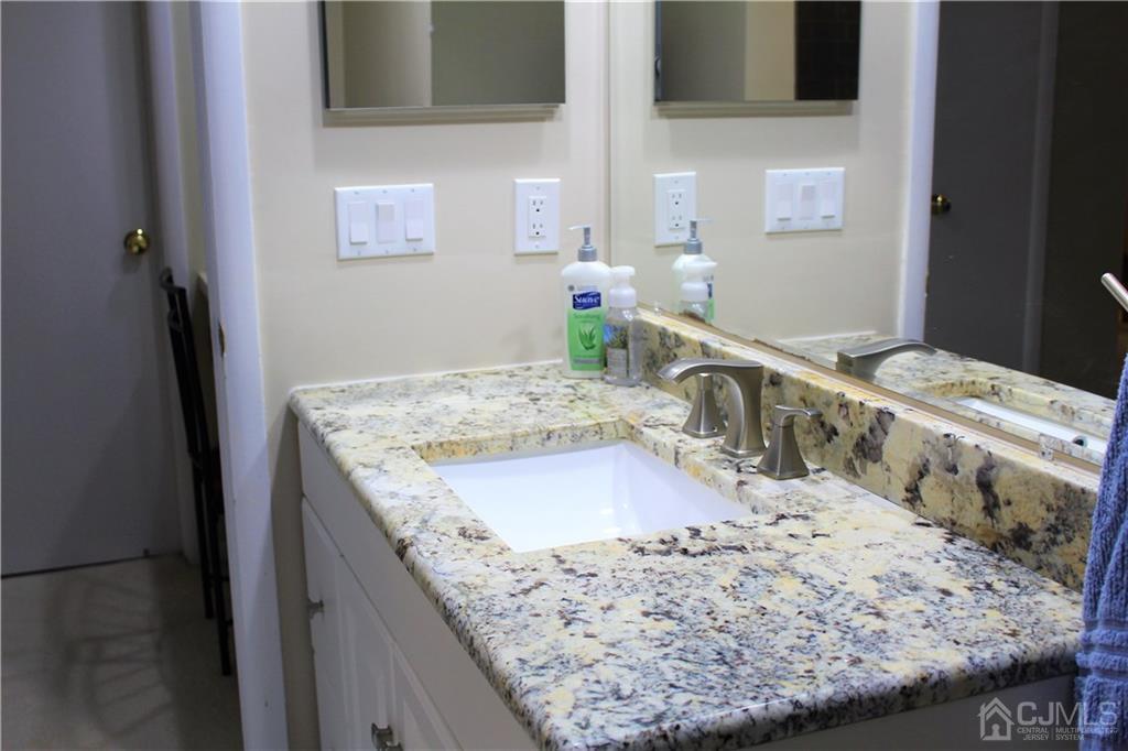 4602 Stonehedge Road, Unit 4602 Edison, NJ 08820 - Photo 20 of 25 a bathroom with a granite countertop sink and a mirror