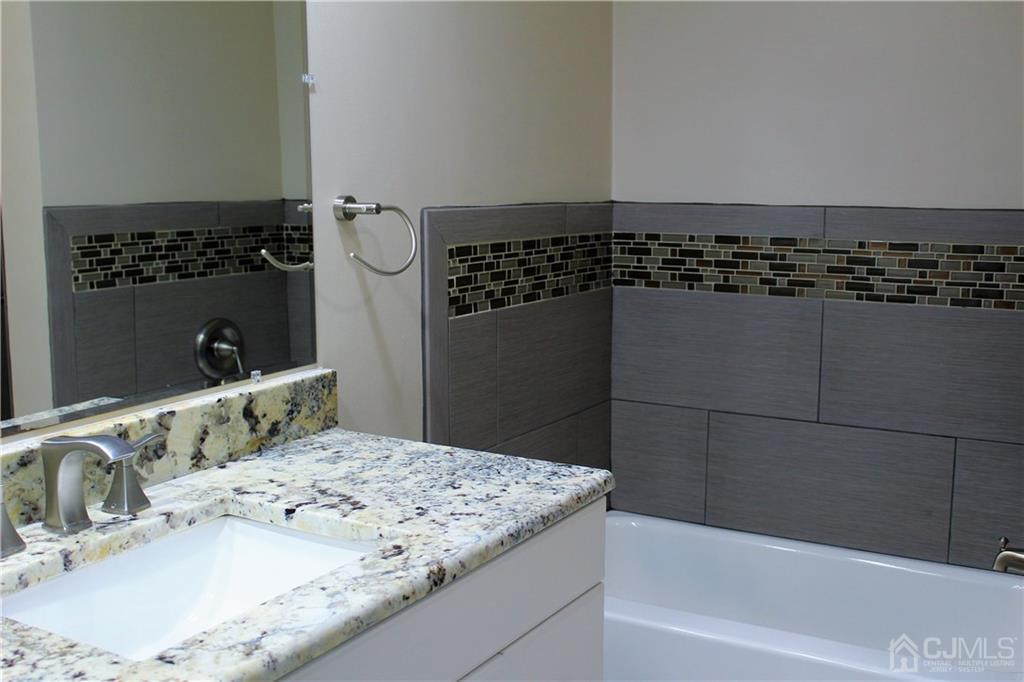 4602 Stonehedge Road, Unit 4602 Edison, NJ 08820 - Photo 21 of 25 a bathroom with a granite countertop sink and a mirror