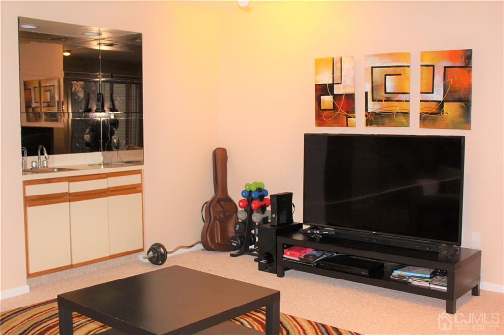 4602 Stonehedge Road, Unit 4602 Edison, NJ 08820 - Photo 23 of 25 a living room with furniture flat screen tv and gym equipment