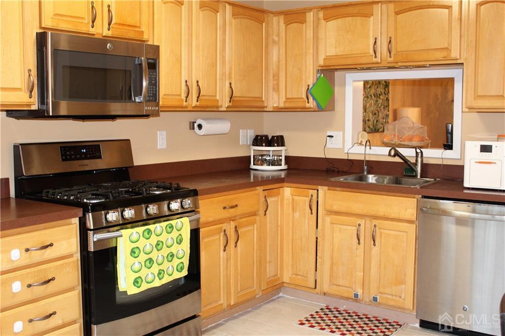 4602 Stonehedge Road, Unit 4602 Edison, NJ 08820 - Photo 9 of 25 a kitchen with stainless steel appliances granite countertop a stove a sink and a microwave