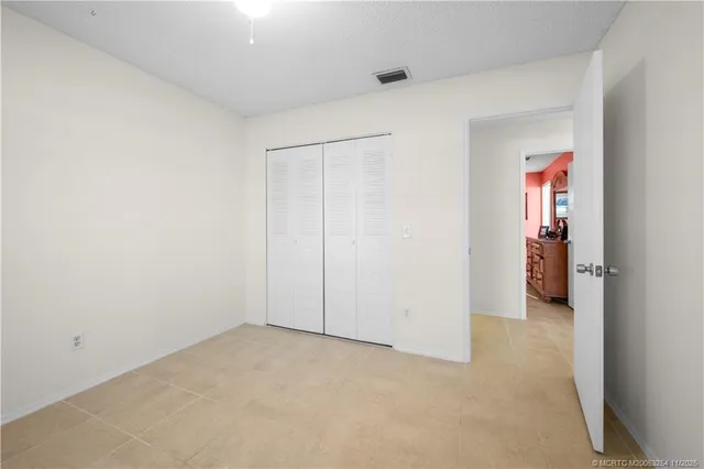 an empty room with a chandelier fan and windows