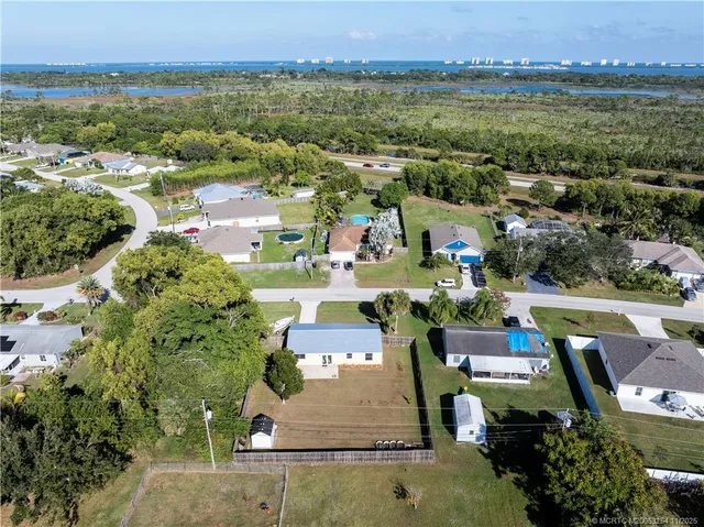 an aerial view of a house with swimming pool and large trees