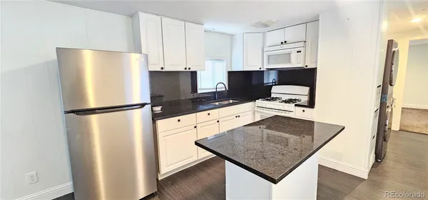 a kitchen with stainless steel appliances granite countertop a refrigerator a stove and a sink