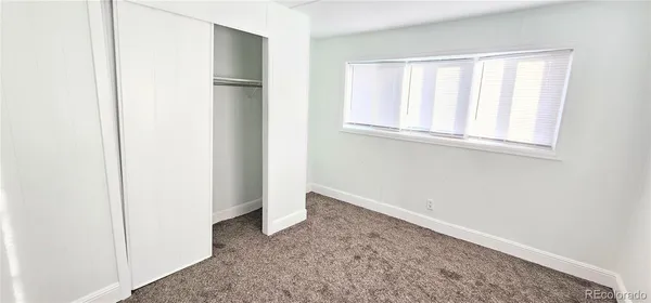 a view of an empty room with windows and closet