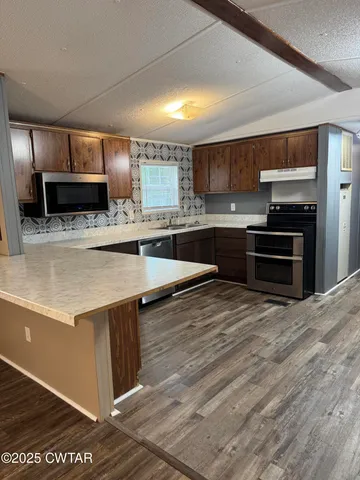 a kitchen with stainless steel appliances kitchen island granite countertop a stove a sink and a refrigerator