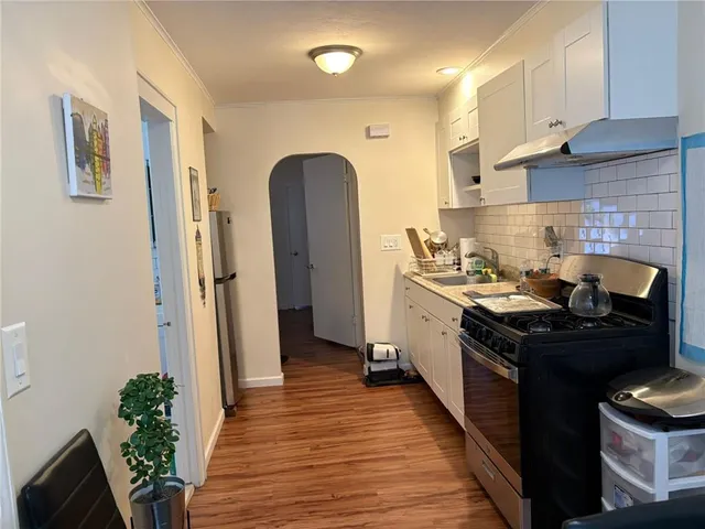 a kitchen with stainless steel appliances granite countertop a stove a sink dishwasher and a refrigerator with wooden floor