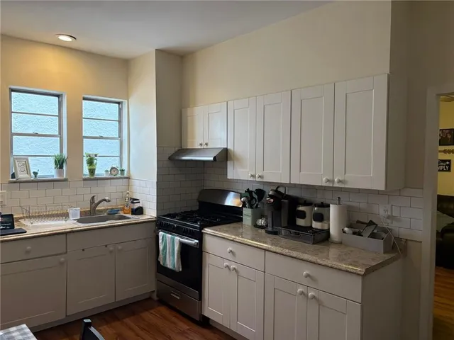 a kitchen with stainless steel appliances granite countertop a sink a stove and cabinets