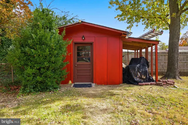 a view of a wooden house with large trees and a small yard